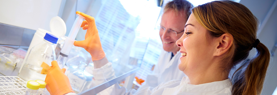 Scientists looking at tubes and smiling.
